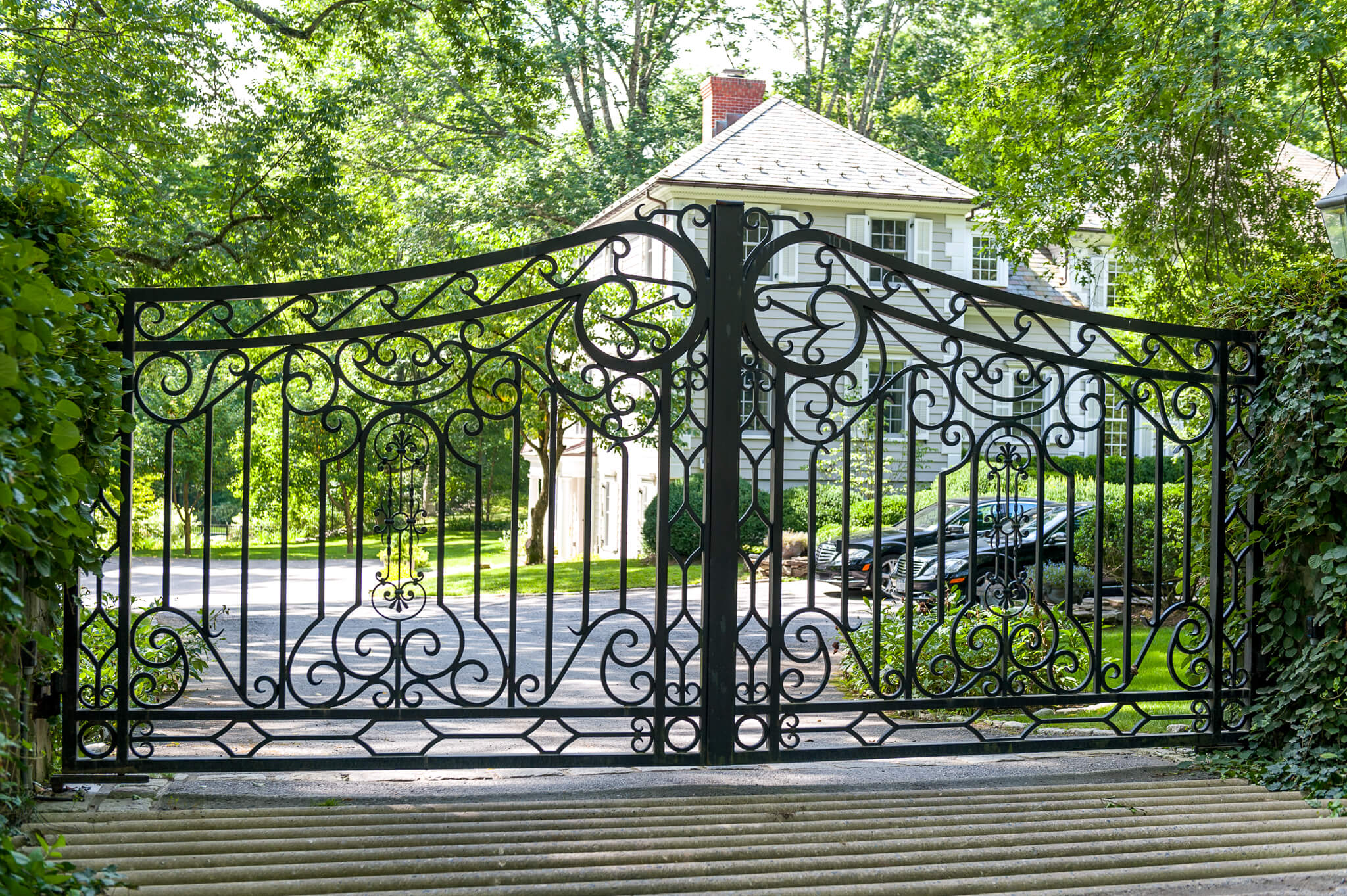 Decorative metal driveway gate in front of a house