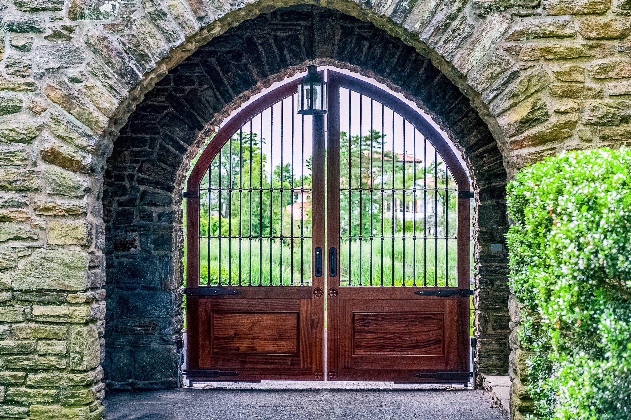 Tall wood driveway gate in a stone entryway